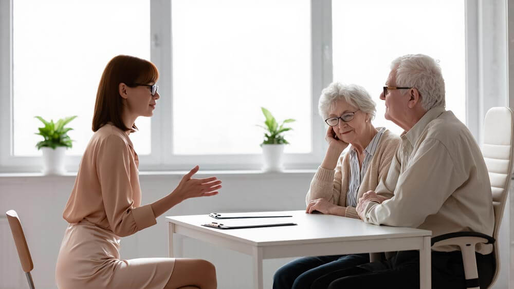 A senior couple discussing health insurance options with a broker