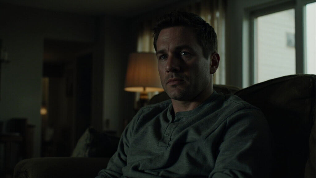 Adult son listening uncomfortably as his parent speaks critically during a tense moment