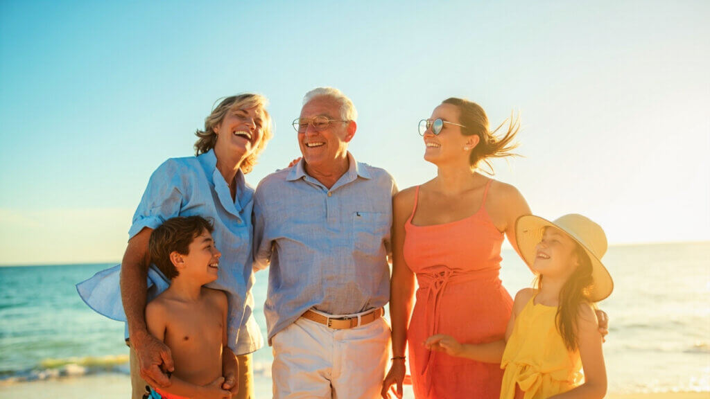 Grandparents, parents, and children posing happily together on a sunny beach
